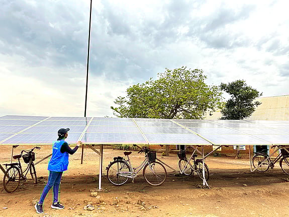 Stora solceller utplacerade på väldigt torr mark. En man står och tittar på dem.