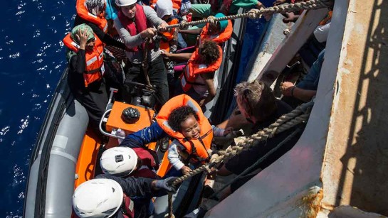 En litet barn lyfts från en gummibåt ombord till sök- och räddningsfartyget Sea Watch. 