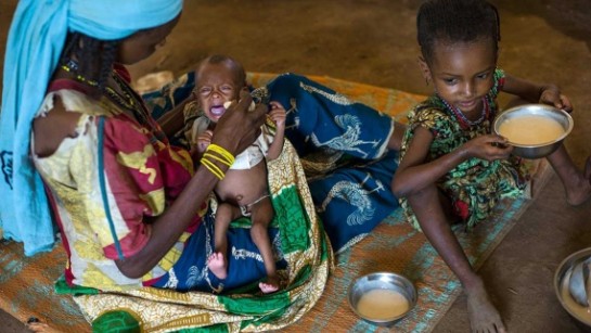Habiba ger sin nyfödda dotter Ramatou näringsrik gröt. Tusentals människor på flykt i Afrika lider av matbrist och får näringstillskott av UNHCR för att överleva. 