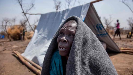 Emelda Peter är 63 år från Sydsudan. Hon kom till flyktinglägret Rhino i Uganda i januari. Hon sitter under sin filt trots den varma kvällsolen: &quot;Jag fryser fortfarande&quot;, säger hon. 