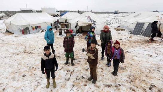 Barn på flykt i norra Syrien står i snön utanför tälten i lägret Azaz.