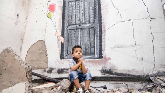 Adham, sex år, sitter i ett förstört hus i Aden. Många familjer har tvingats lämna sina hem på grund av den svåra konflikten i Jemen. 