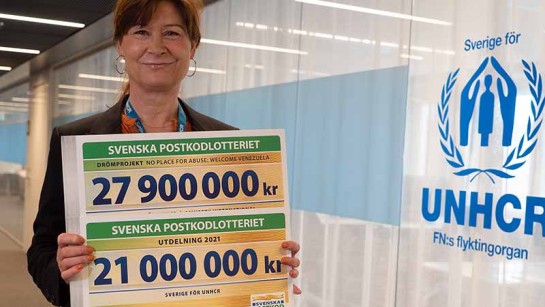 Åsa Widell visar upp checkarna från Postkodlotteriet som ska hjälpa människor på flykt.