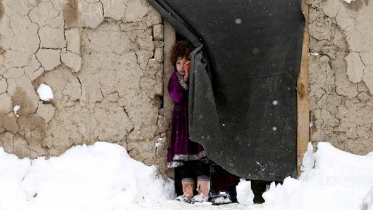 En flicka på flykt i Afghanistan står i dörren till sitt boende under ett snöoväder i Kabul.