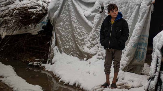 En flyktingpojke står utanför sitt tält i Bekaadalen i Libanon.