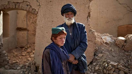 Sayed Mohammad* och hans son Adbul Wadood* står utanför sitt förstörda hem i Marja, södra Afghanistan.