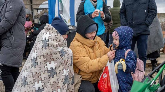 En mamma försöker hålla sitt barn varmt medan de väntar att passera gränsen till Moldavien.