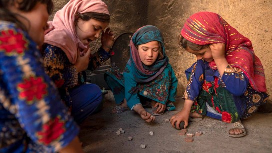 Barnen lekar med stenar i ett läger för familjer på flykt utanför Kandahar.