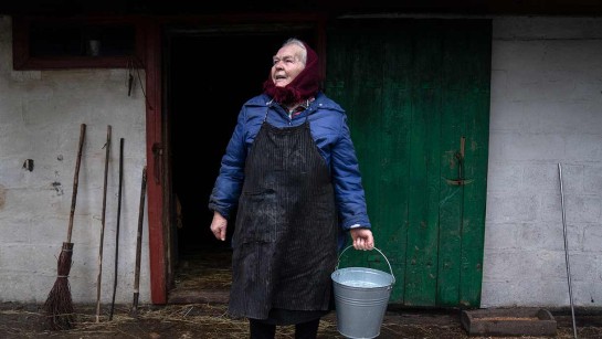 Kateryna står framför ladan där de gömde sig från ryska stridsvagnar. Hennes ko överlevde kriget under tiden familjen var på flykt.