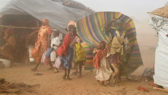 Kvinnor och barn från Sudan är på flykt mitt i en sandstorm.