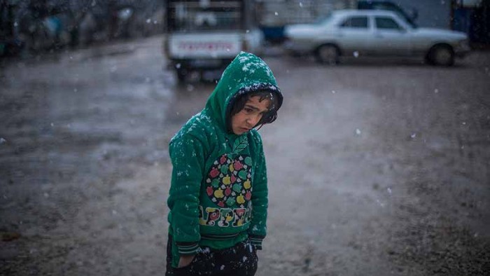 En pojke på flykt från Syrien går genom ett tältläger i Libanon. Vill du skänka en gåva till UNHCR:s arbete för människor på flykt?
