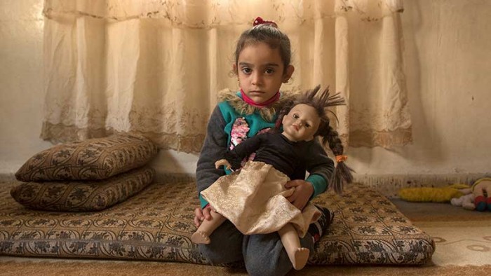 En flicka på flykt från Syrien håller sin docka i famnen. Hon är  flykting som bor i Ammans fattigaste kvarter.